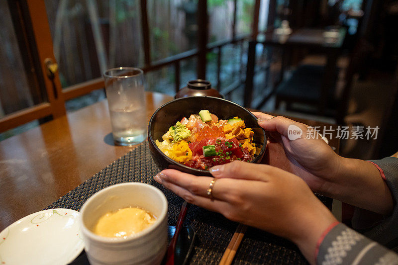 独自旅行的女人穿着和服/袴拿着海鲜顿饭当午餐